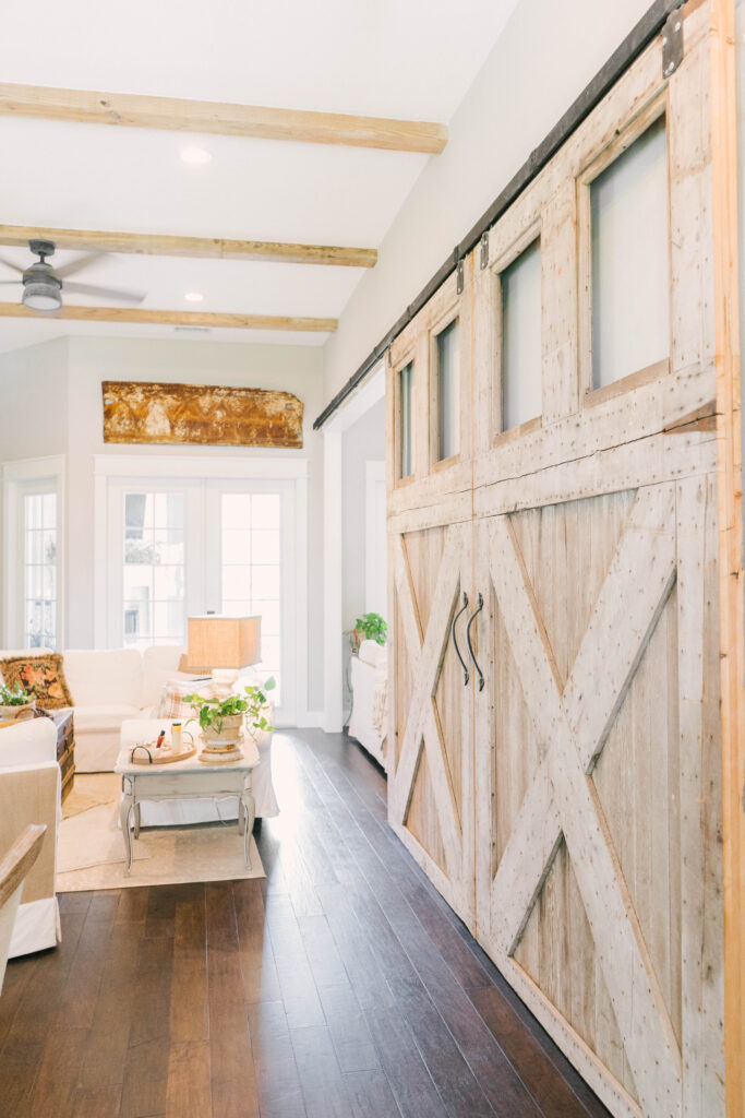 large barn doors inside living room with wood ceiling beams dark wood floors white sofa 