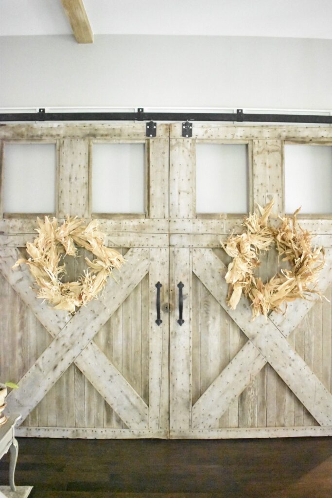 large cornhusk wreaths hanging on 2 large barn doors inside my living room 