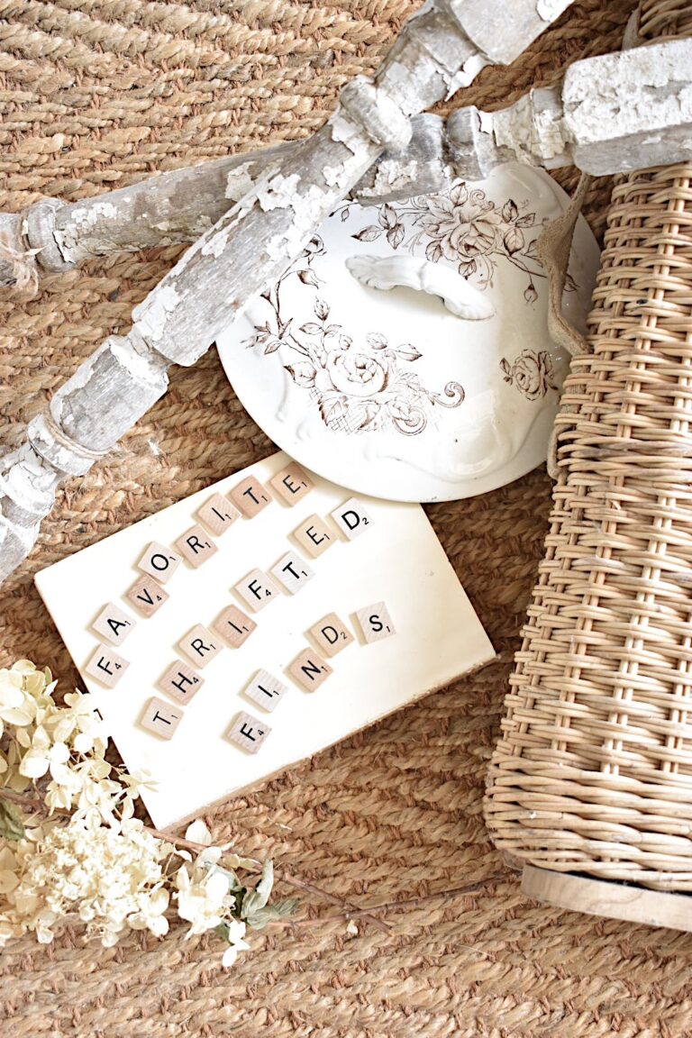 overhead view of my favorite thrifted finds written in scabble tiles with chippy spindles lid of brown transferware bowl vintage book and a basket on a woven rug background