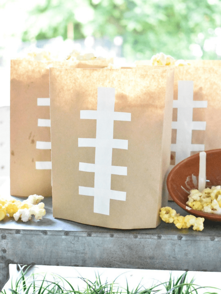 brown lunch sacks with white electrical tape cut and stuck on front to resemble the threads on a football, bags are filled with popcorn