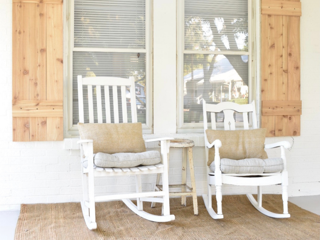 2 white rockers on front porch of white painted brick house with cedar shutters 