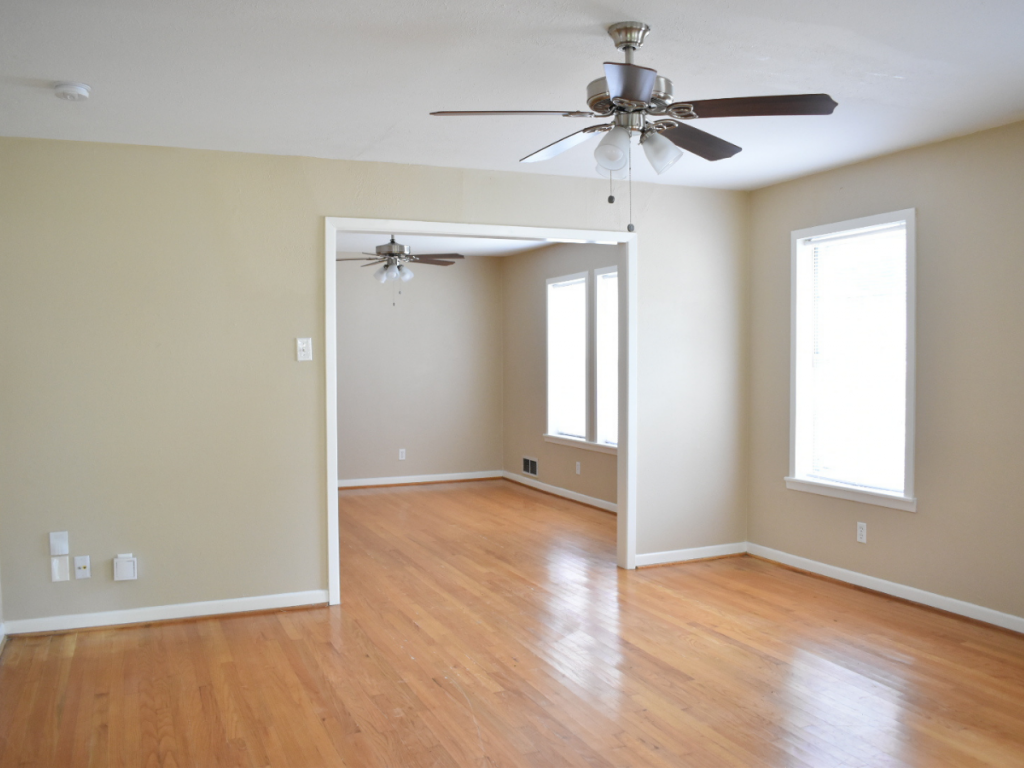 living room with tan wall white trim ceiling fan light hardwood floors no furniture