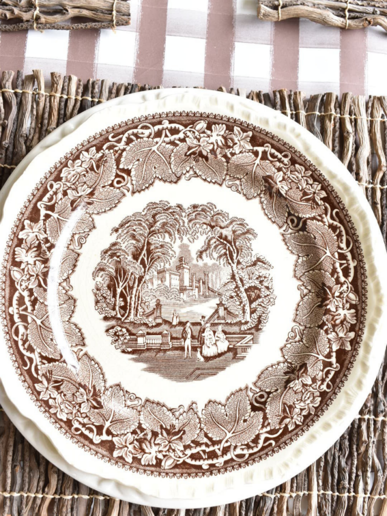 twig placemat with a large white dinner plate layered with a smaller brown transferware dinner plate