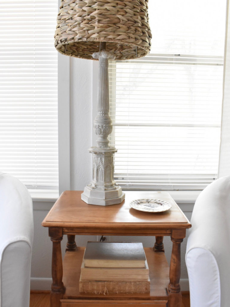 small wood side table with lamp and coaster beside white chair