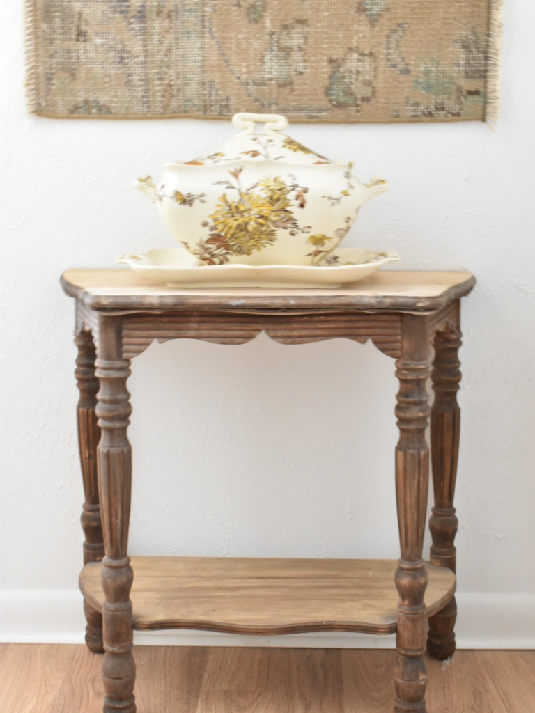 small dark wood table at end of white hallway with vintage soup tureen on top