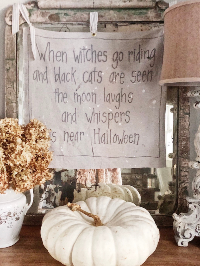 witch saying on drop cloth with black fabric marker writing hanging on vintage mirror white heirloom pumpkin on dresser in front of sign.