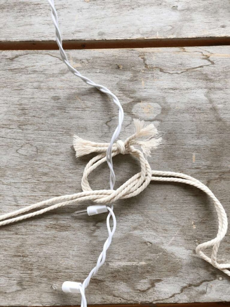 macrame cording being wrapped around strand of white Christmas lights