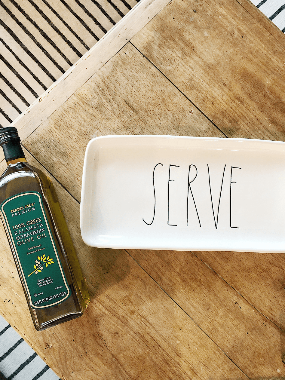 white rectangle platter that says serve and bottle of olive oil beside it on wood table top