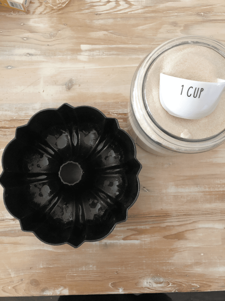 overhead view of bundt pan and jar of sugar with 1 cup measuring cup inside