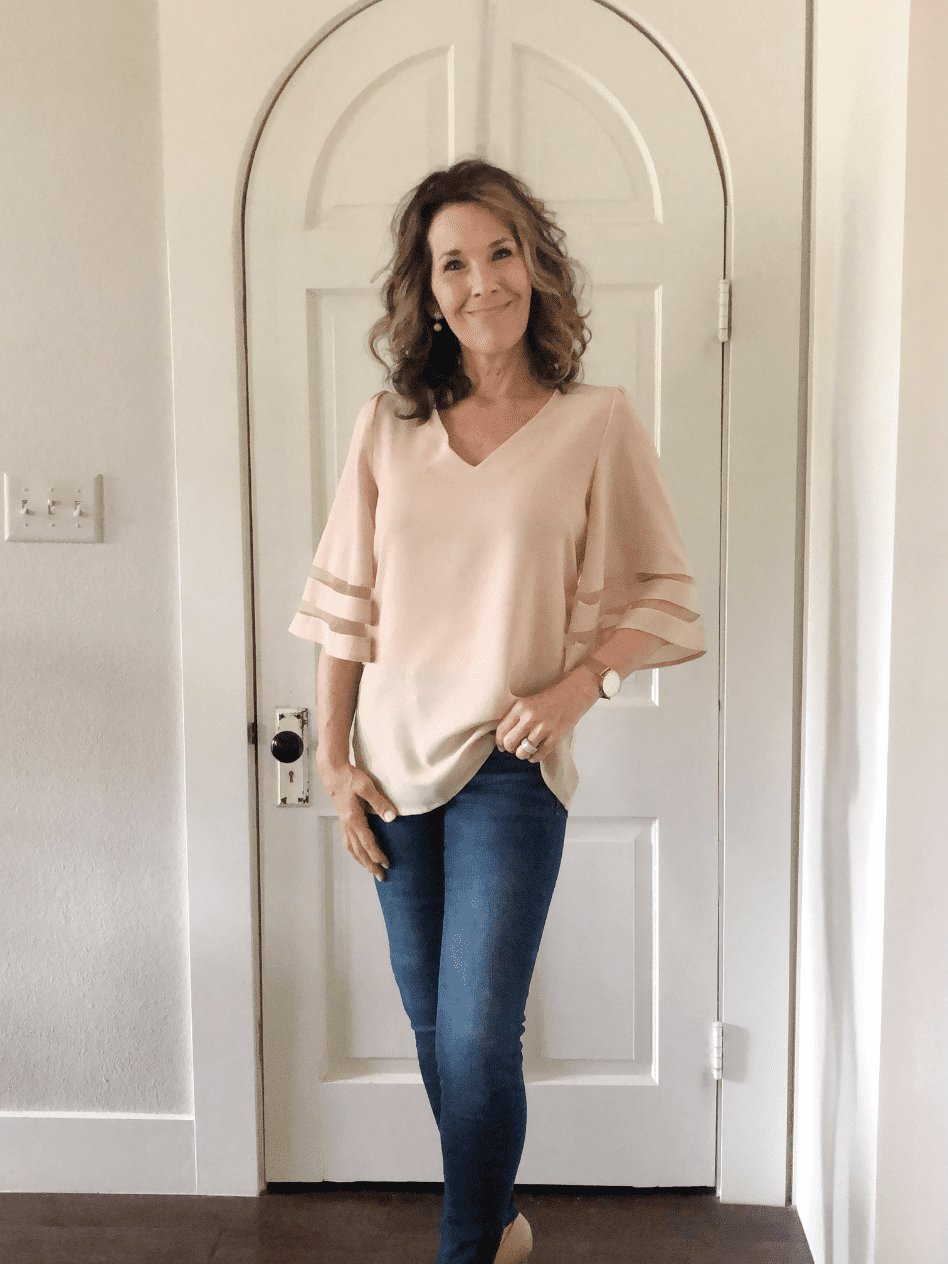 woman modeling ivory silk bell sleeve blouse with jeans