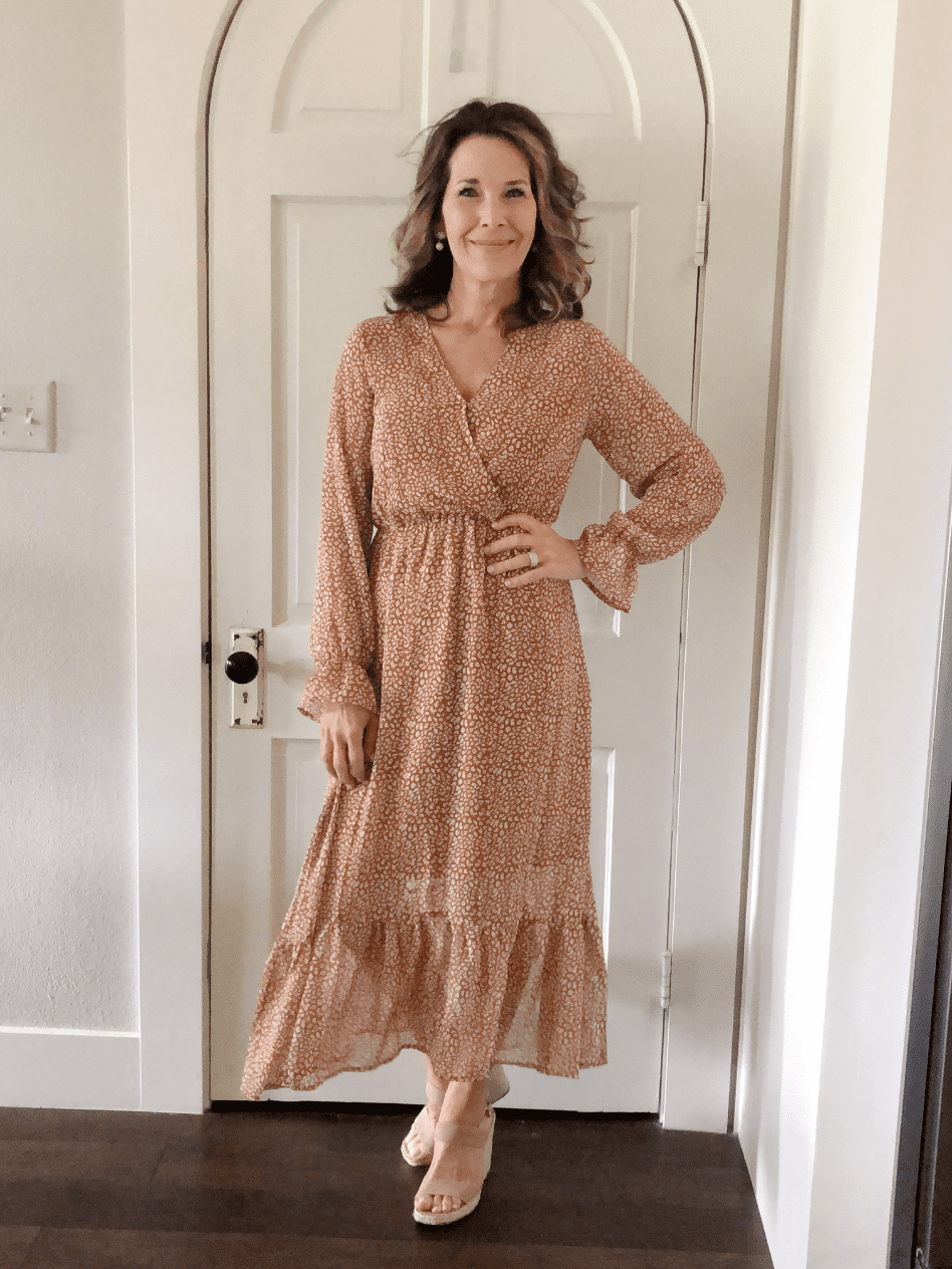 woman modeling caramel color floral print v neck wrap dress with ruffle trim at bottom and at sleeves