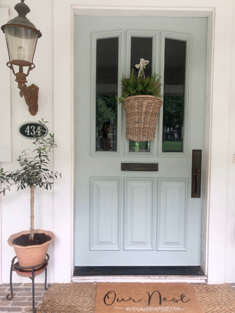 light blue farmhouse front door with wicker basket with flowers inside 