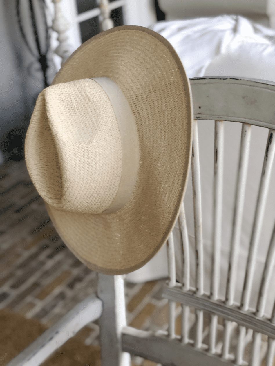 straw cowboy hat hanging on side of white spindle back chair