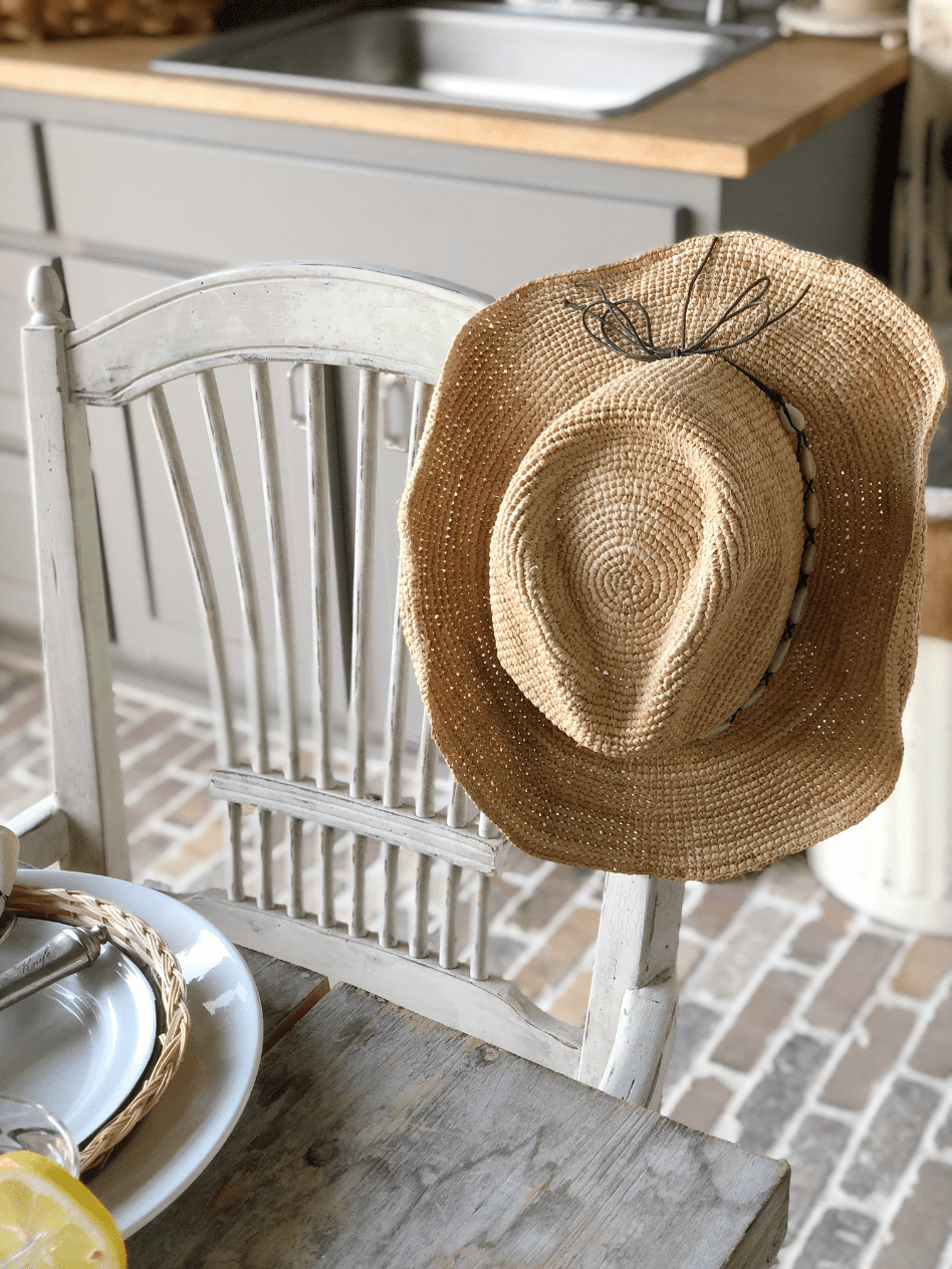 straw cowboy hat hanging on side of white spindle back chair