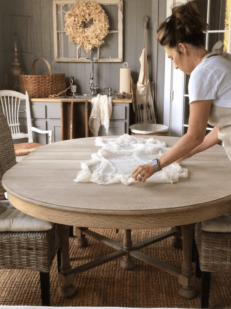 woman placing a cheesecloth on dining table for table runner