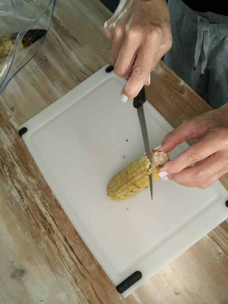 cutting grilled corn off cob for black bean and corn nachos