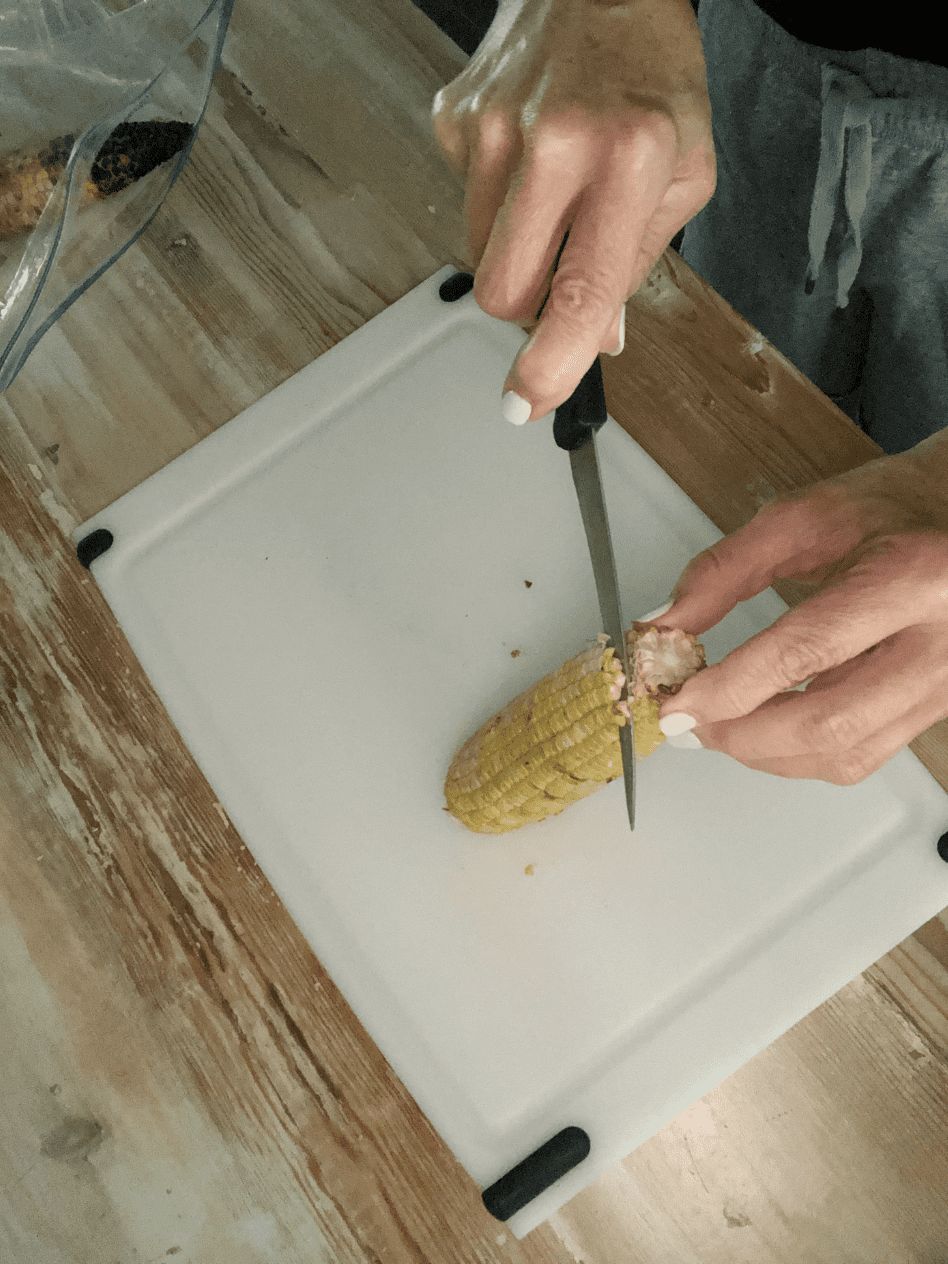 cutting grilled corn off cob for roasted corn and shrimp chowder