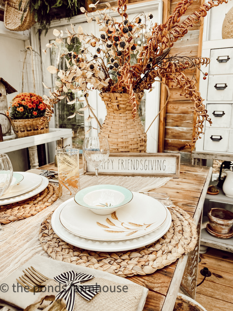 friendsgiving brunch tablscape woven placemats leaf pattern on white dishes basket with fall florals centerpiece