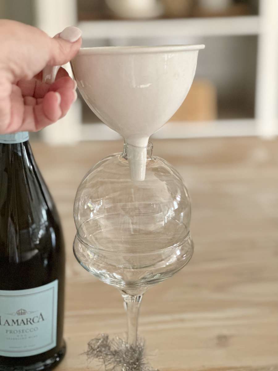 clear glass christmas ornament ball sitting in martini glass with funnel over it