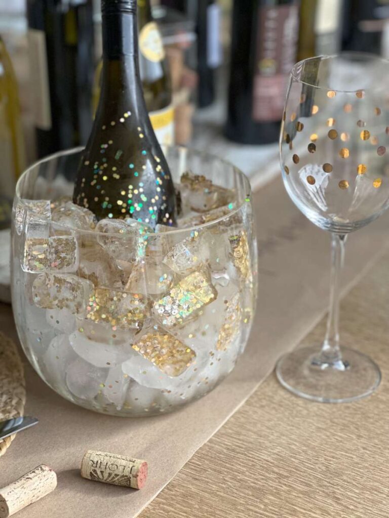 glitter ice cubes in clear ice bucket with bottle of wine