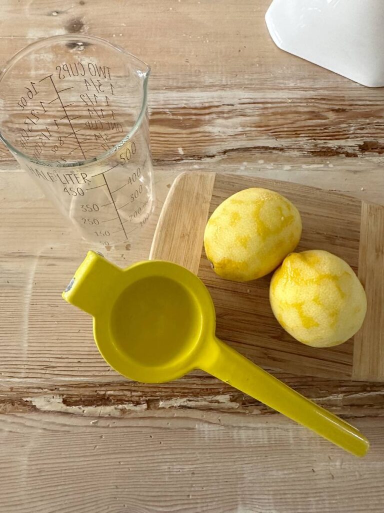 2 lemons and lemon juicer and measuring cup