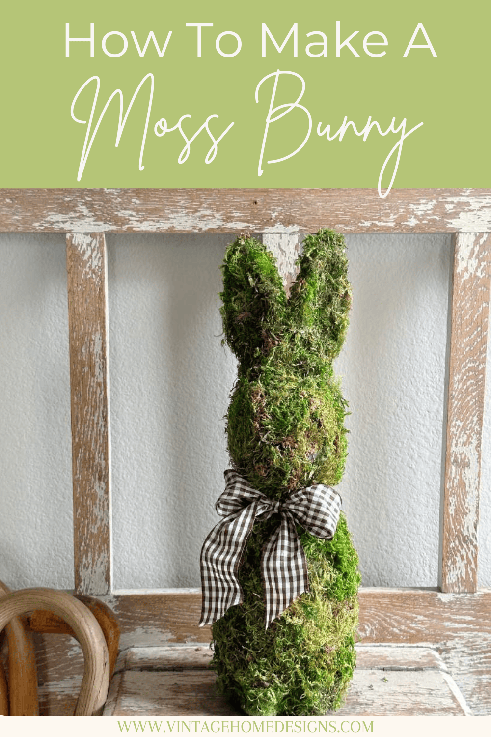 A moss covered bunny DIY figure with a brown and white checkered ribbon bow sits on a wooden bench in front of a rustic window frame; text above reads "How To Make A Moss Bunny.