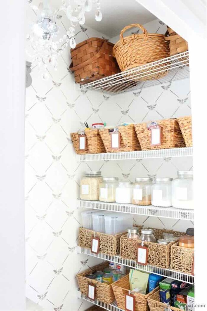 pantry with wallpaper baskets and glass cannisters on white wire shelves