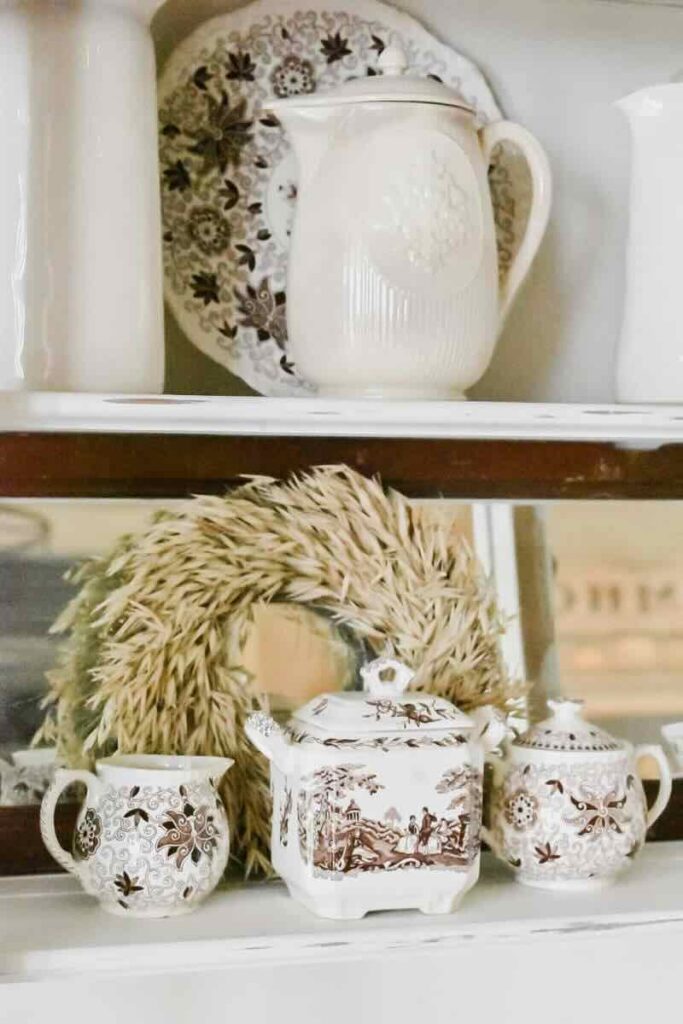 china hutch with brown transferware straw wreath and white pitchers