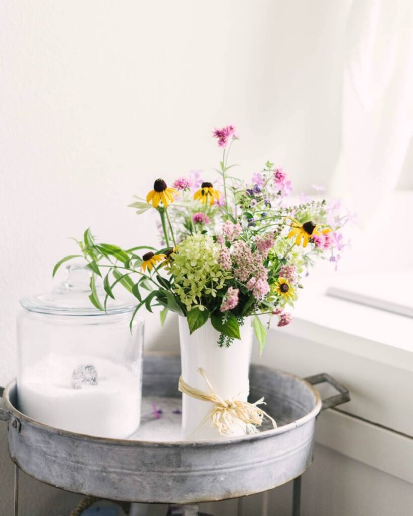 wild flower arrangement in white vase on galvanized tray table