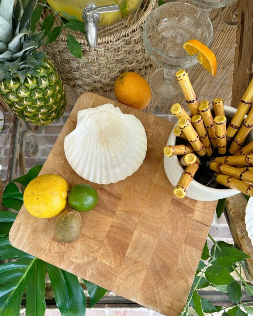 lemons lines and oranges on cutting board with seashell plate and bamboo handle silverware