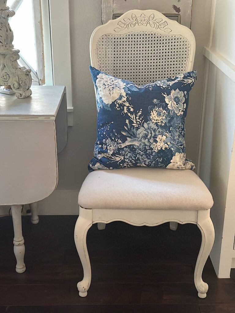 blue floral pillow in white cane back chair for summer decor