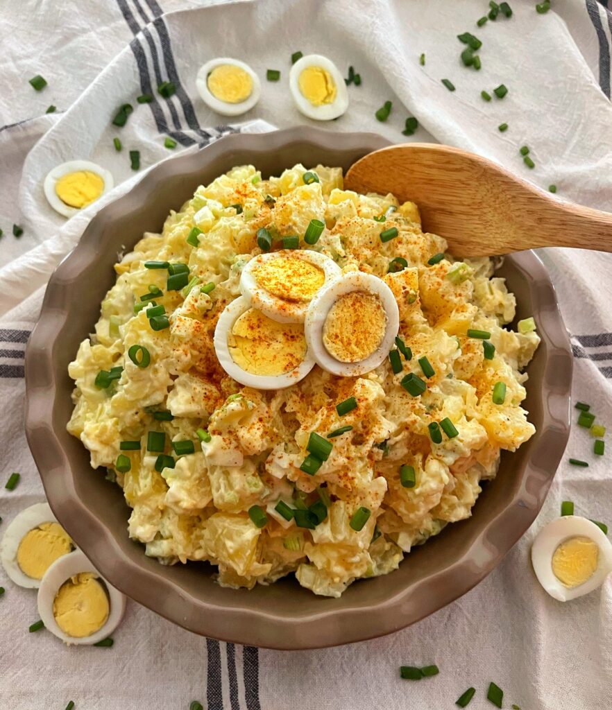 potato salad in large wooden serving bowl with egg slices on top