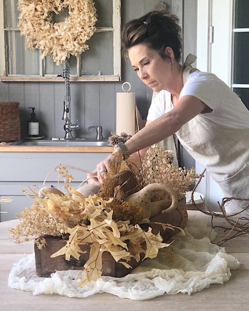 woman arranging fall table centerpiece arrangement