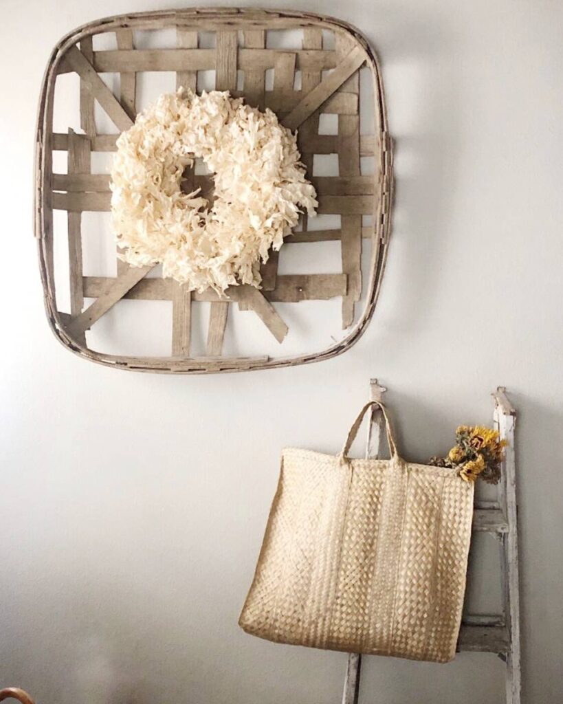 tobacco basket with fall wreath inside vintage ladder with straw tote on it