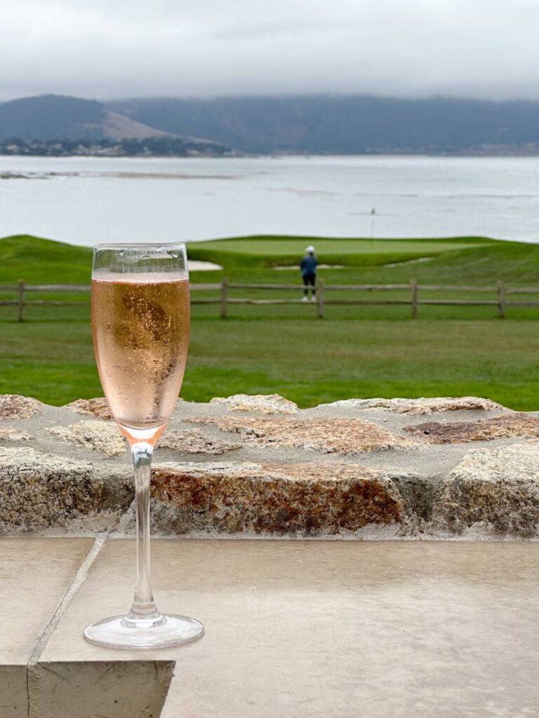 glass of champagne with 18th green of Pebble Beach Golf Course in background