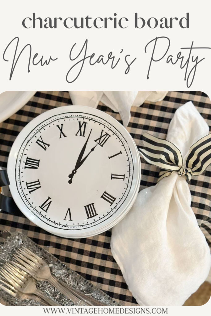 white clock plates stack of white napkins with black striped ribbon tied and forks in clear glass tray sitting on black check tablecloth on table