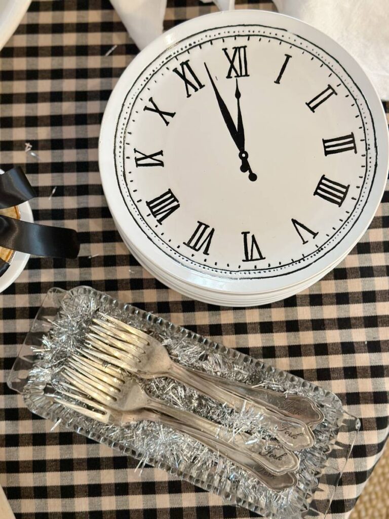 white clock plates and forks in clear glass tray sitting on black check tablecloth on table