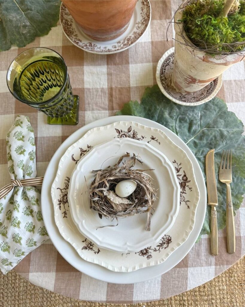 white salad plate with birds nest on top green block print napkin gold flatware on cabbage leaf placemat for spring place setting