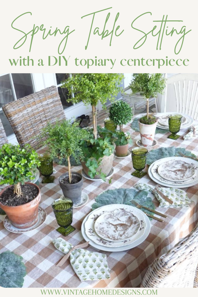 brown check tablecloth with brown pattern bunny plate green block print napkin gold flatware on cabbage leaf placemat at 6 place settings for spring table topiaries down center of table