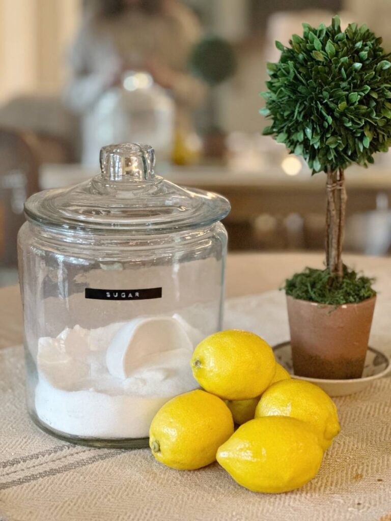 glass cannister of sugar lemons piled beside and faux topiary