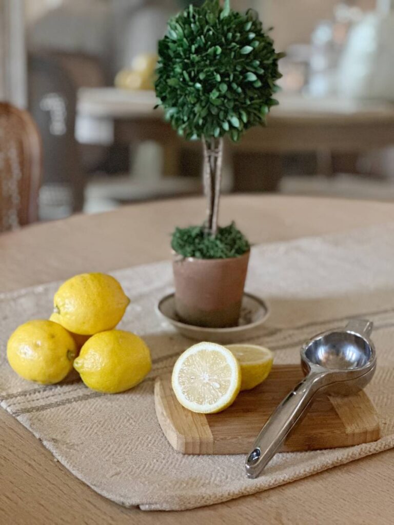 whole lemons and 1 cut lemon with lemon squeezer on cutting board