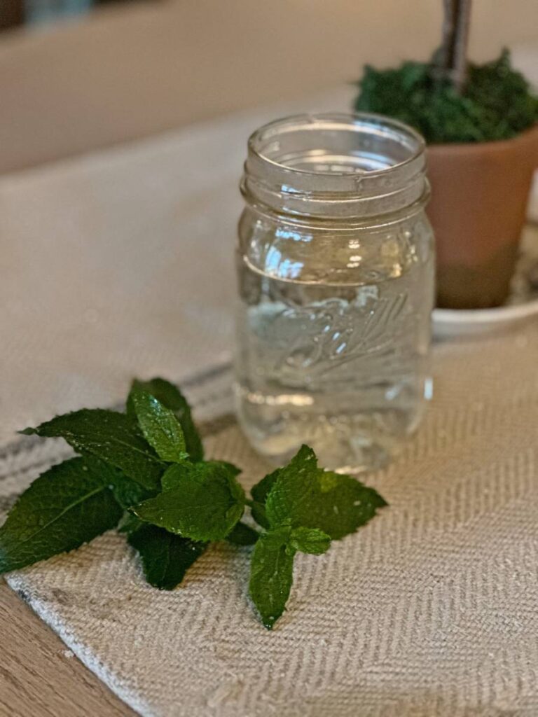 mint simple syrup in glass mason jar with mint sprigs beside it