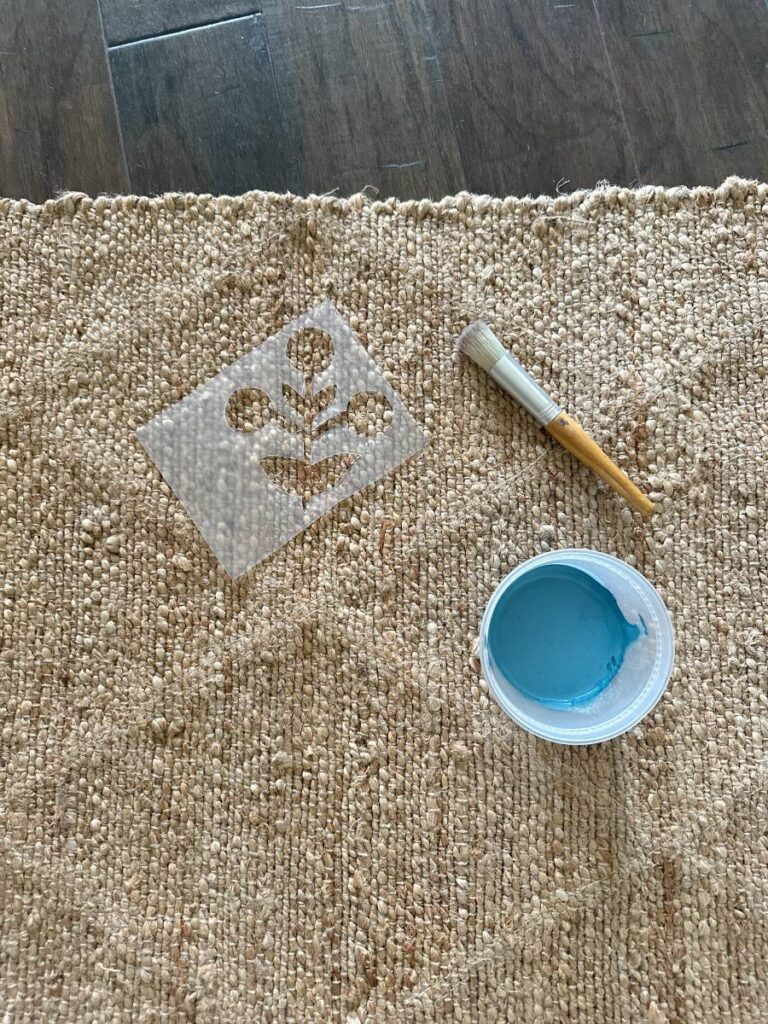 jute rug with container of blue paint and stencil and stencil brush