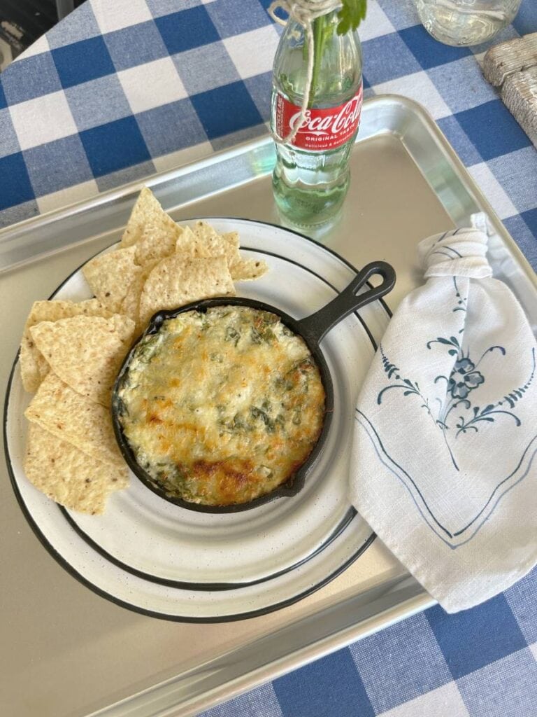 spinach artichoke dip in mini cast iron skillet on white plate with tortilla chips