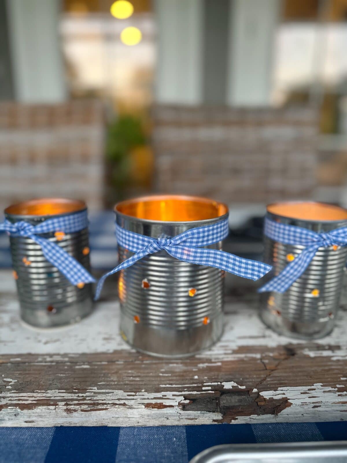 3 tin can luminarias on white chippy board for table centerpiece