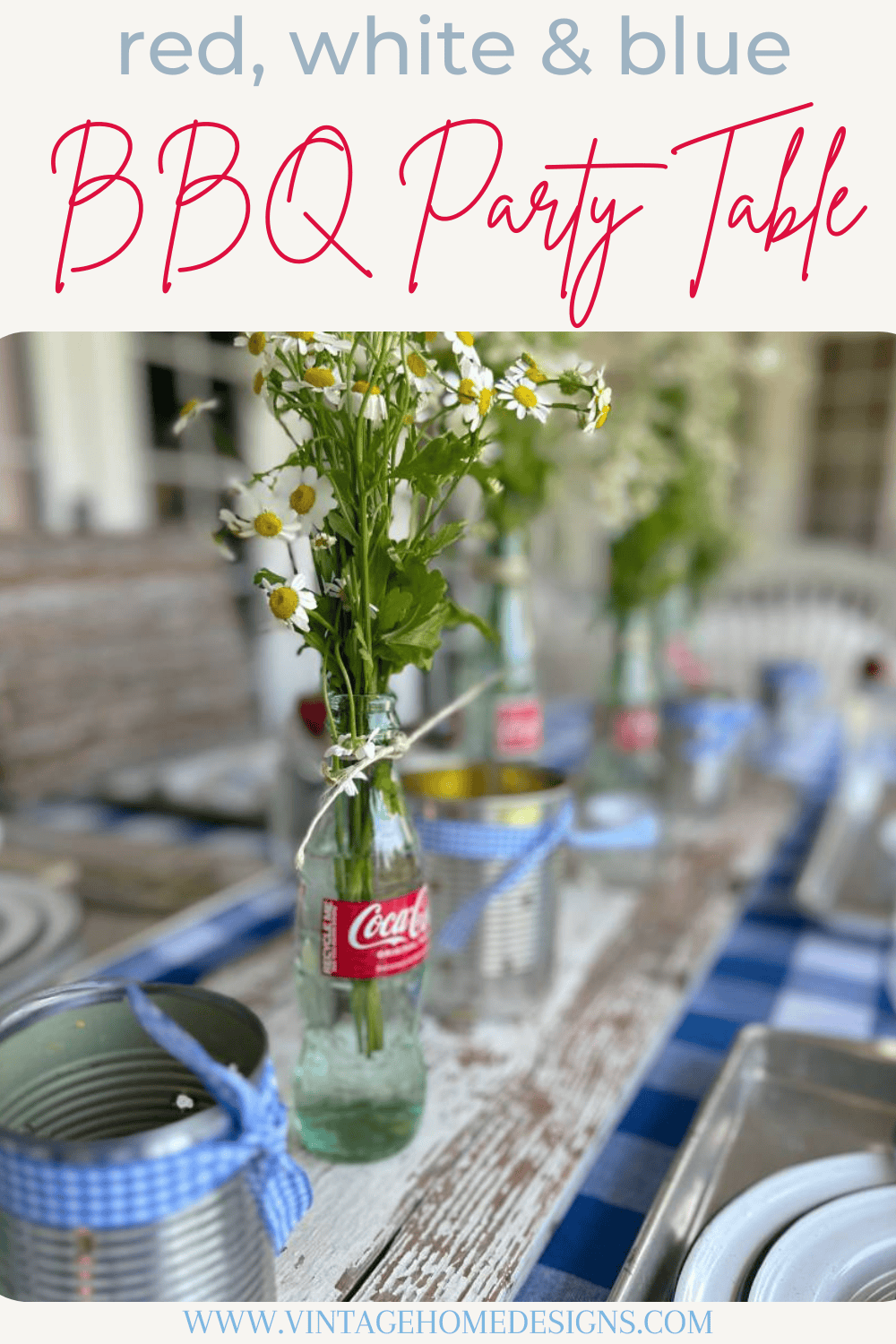 white chippy board down center of table on blue and white check tablecloth 6 glass coke bottles with small white daisies tin can luminarias on top of board for table centerpiece