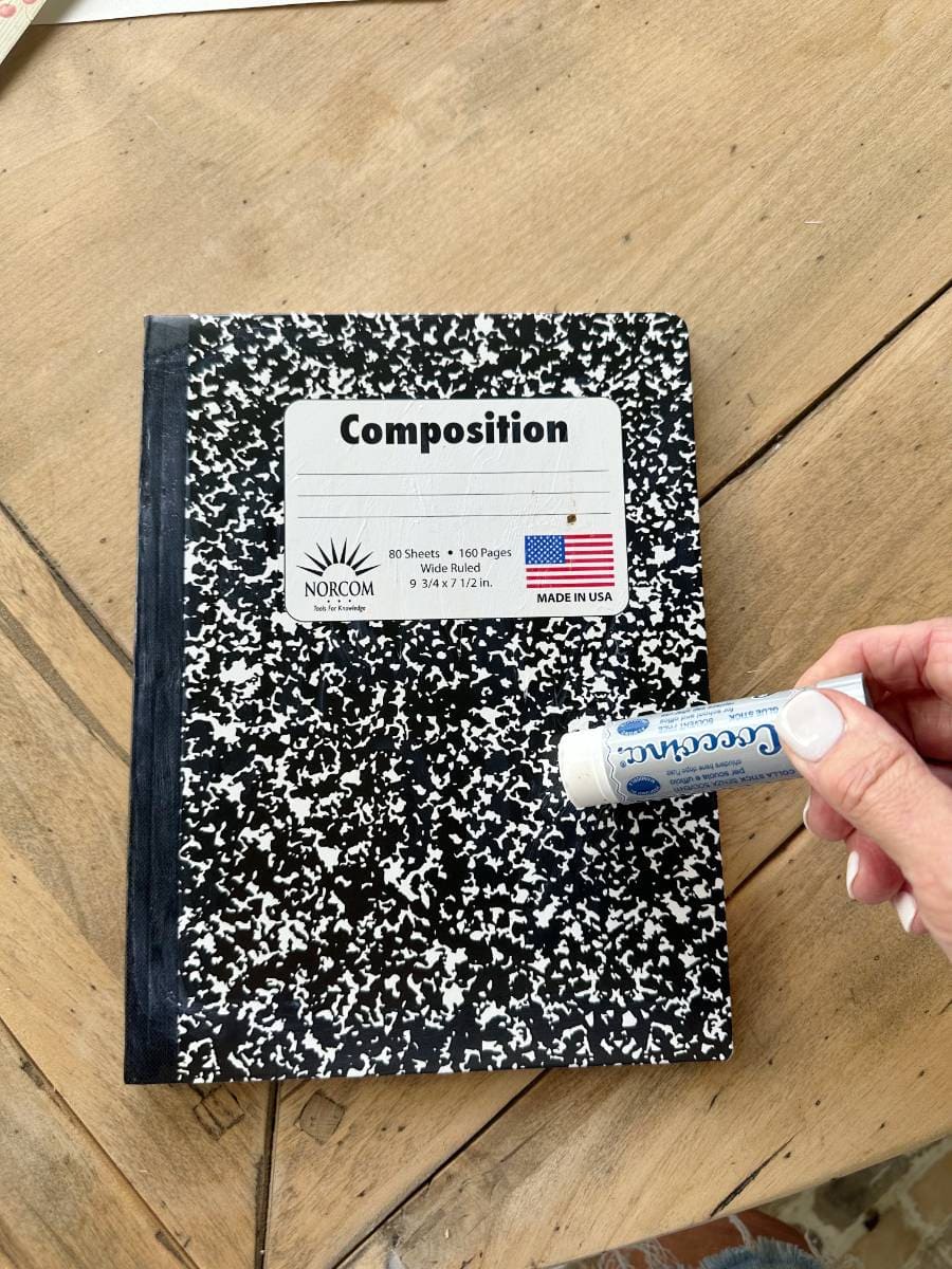 composition notebook and glue stick on wood table