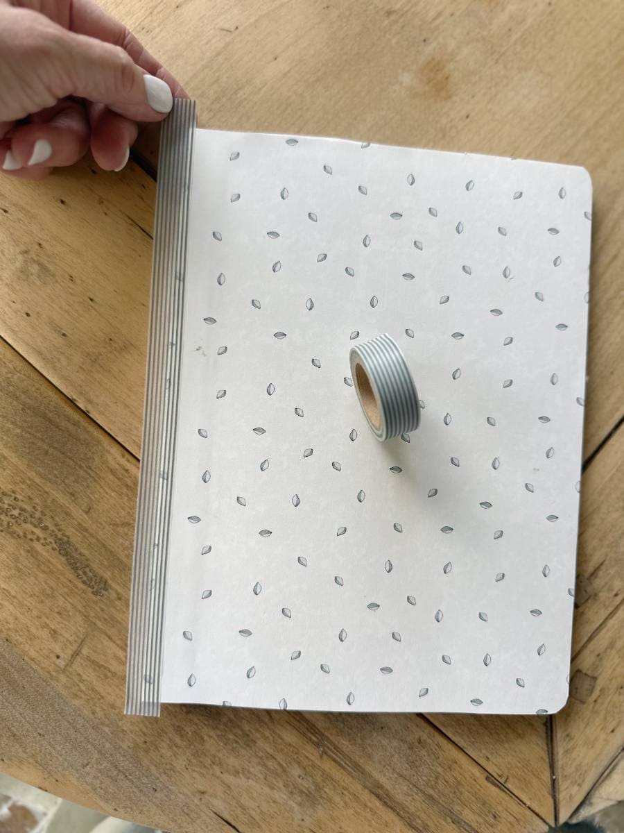 composition notebook covered with decorative paper and washi tape on binding