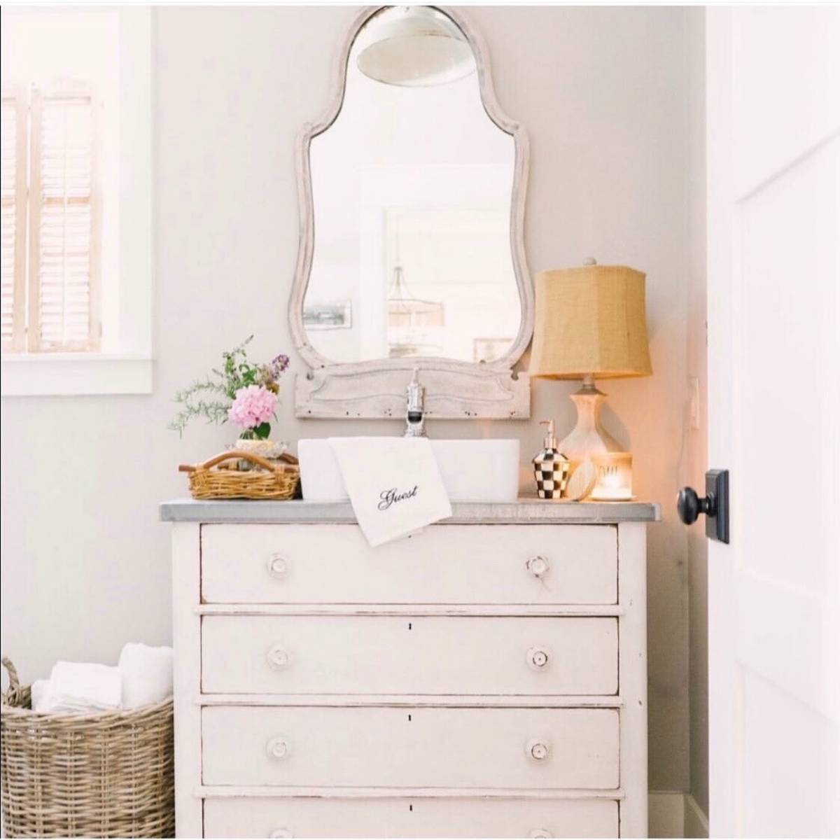 guest bathroom vanity with lamp candle and vase of flowers