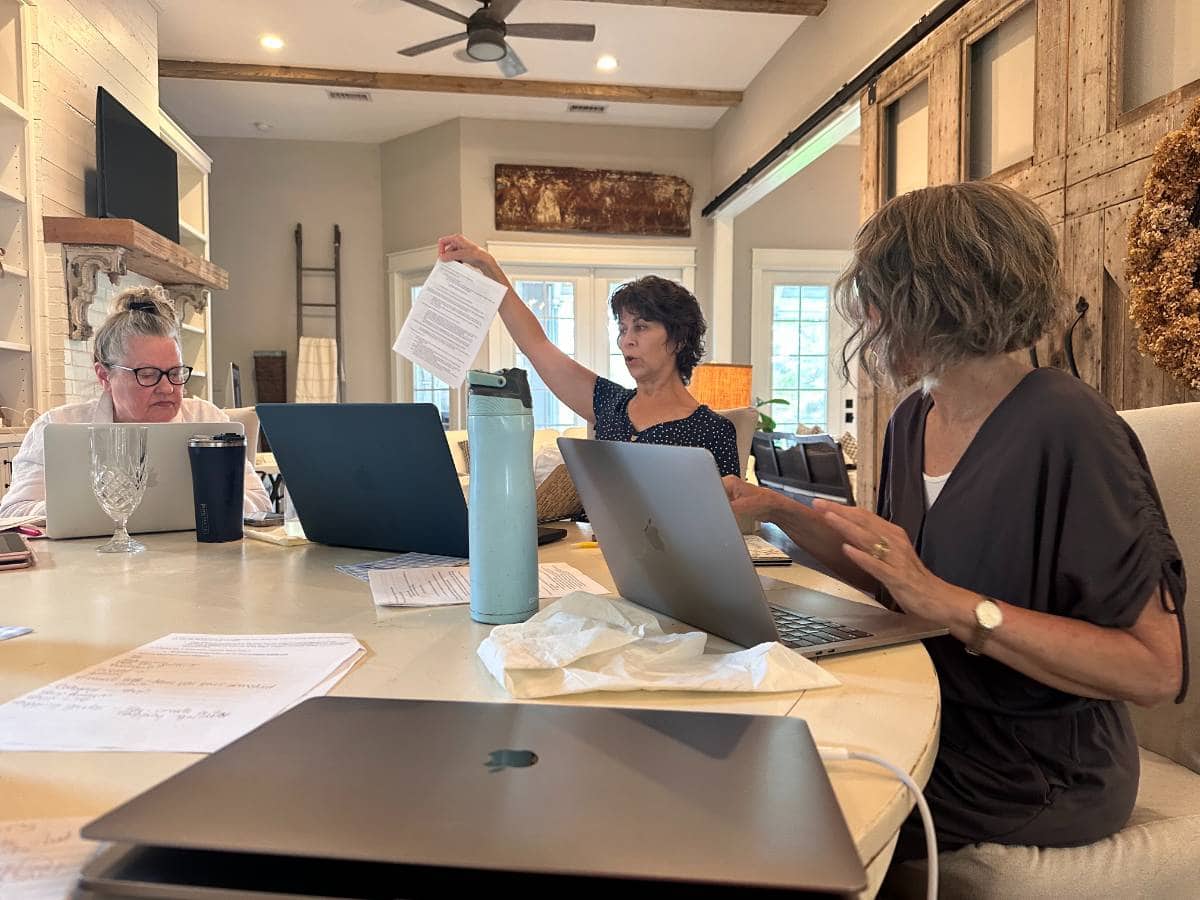 ladies sitting at round white table with computers during creative retreat